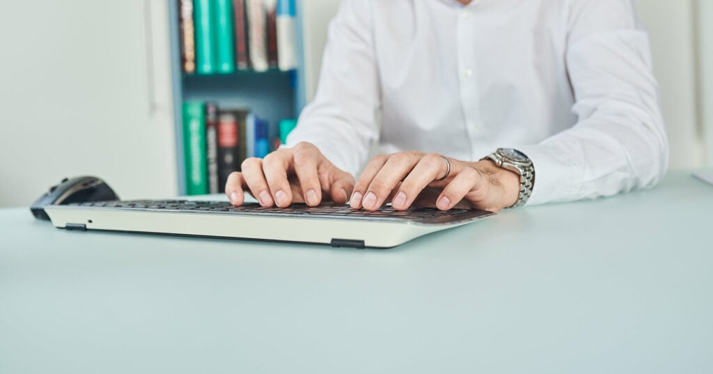 Hände tippen E-Rezept auf einer Computer Tastatur